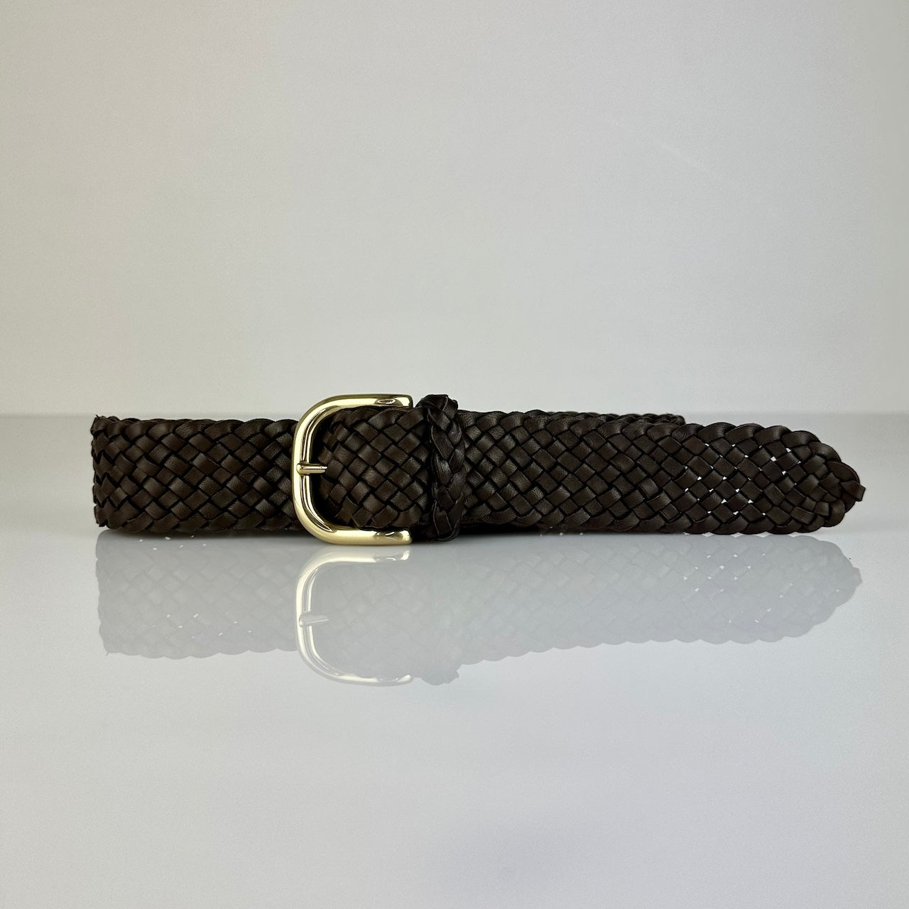 Der Braided Belt 40 in Darkbrown von LABEL17 ist ein Gürtel gefertigt aus geschmeidigem, pflanzlich gegerbtem Lamm-Nappaleder, von Hand geflochten in der Farbe dunkelbraun. Mit Messingschnalle.