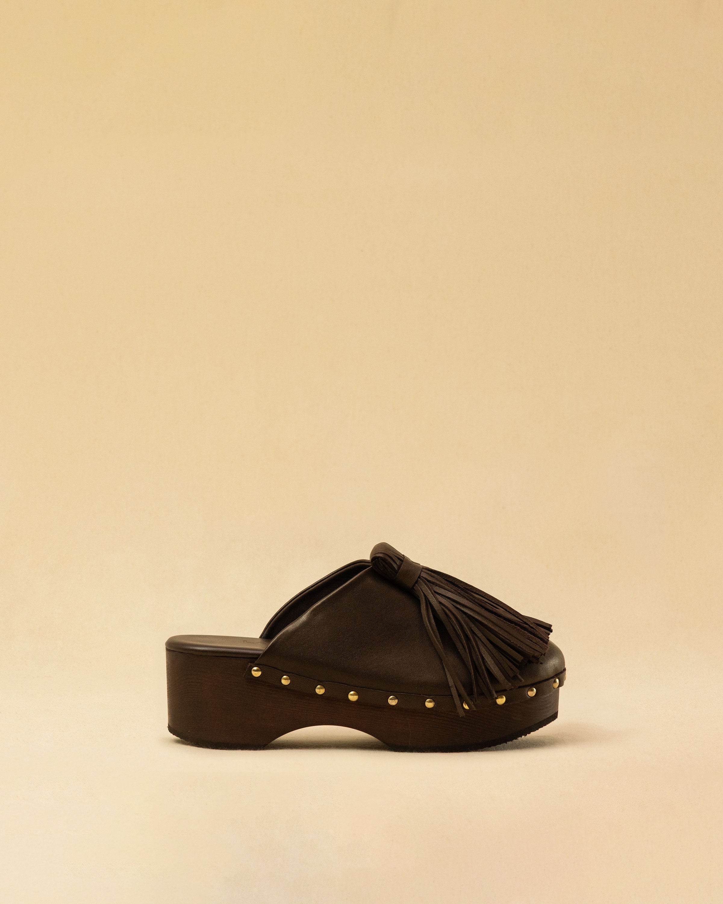 Clogs Choucha in dark brown by LABEL17, crafted from supple, vegetable-tanned lamb nappa leather. A large, soft pompom on top swings elegantly from left to right with each step, adding a playful yet refined touch. The shoe features a durable Vibram sole for comfort and stability. The artisanal craftsmanship enhances the overall aesthetic, making these clogs a true statement piece. Quiet luxury at its best. Handmade in Greece.