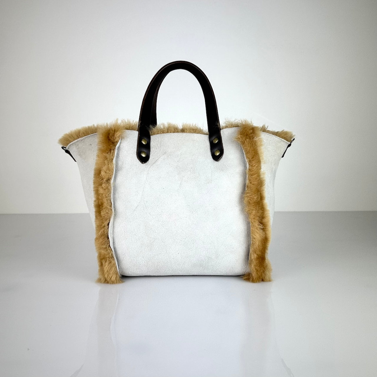 Diese HANDBAG SHEARLING REVERSIBLE, MEDIUM von LABEL17 wird aus luxuriösem Merino-Lammfell gefertigt, das der Tasche einen einzigartigen und stilvollen Look verleiht. Mit dunkelbraunen Griffen aus Sattlerleder und einem abnehmbaren Schulterriemen bietet sie vielseitige Tragemöglichkeiten, egal ob in der Hand oder als Crossbody.
Diese reversible Tasche ist ein Meisterwerk der Schweizer Handwerkskunst und vereint schlichtes Design mit hochwertiger Sattlerarbeit. Jede Tasche ist ein Unikat.