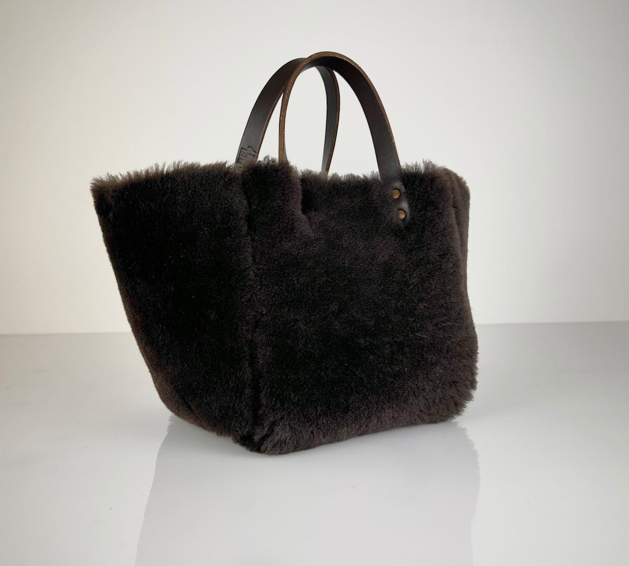 Die HANDBAG SHEARLING REVERSIBLE, MEDIUM von LABEL17 wird aus luxuriösem Merino-Lammfell gefertigt, das der Tasche einen einzigartigen und stilvollen Look verleiht. Mit dunkelbraunen Griffen aus Sattlerleder und einem abnehmbaren Schulterriemen bietet sie vielseitige Tragemöglichkeiten, egal ob in der Hand oder als Crossbody.
Diese reversible Tasche ist ein Meisterwerk der Schweizer Handwerkskunst und vereint schlichtes Design mit hochwertiger Sattlerarbeit. Jede Tasche ist ein Unikat. 