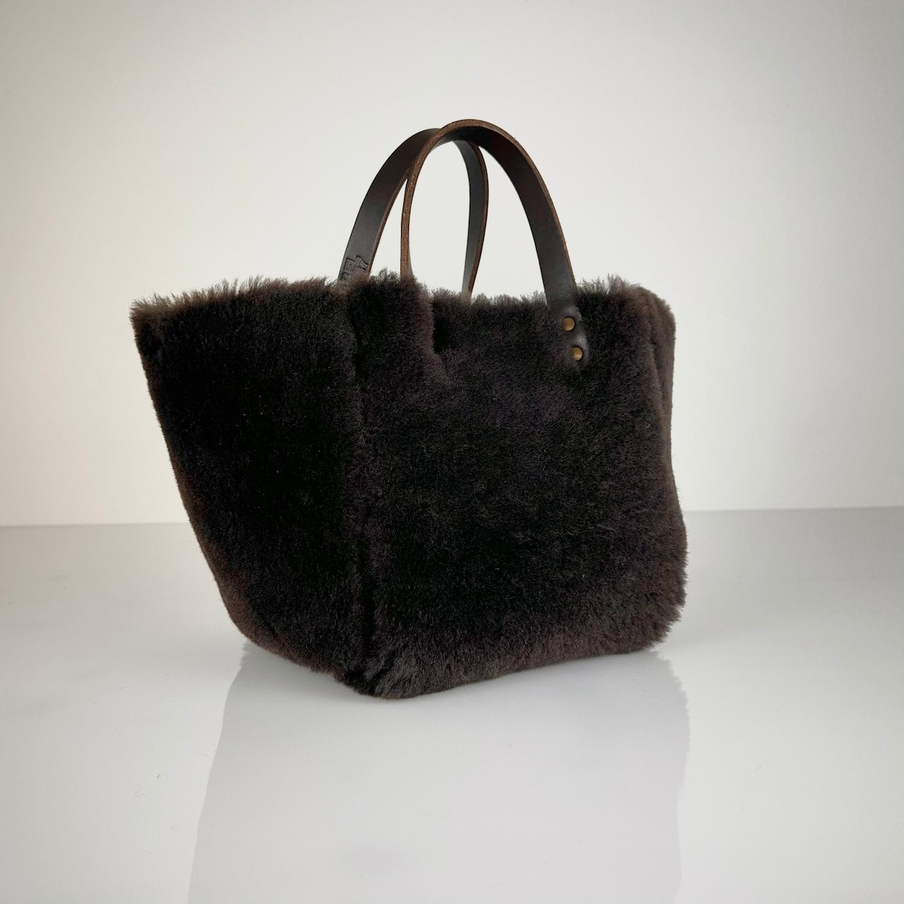 Die HANDBAG SHEARLING REVERSIBLE, MEDIUM von LABEL17 wird aus luxuriösem Merino-Lammfell gefertigt, das der Tasche einen einzigartigen und stilvollen Look verleiht. Mit dunkelbraunen Griffen aus Sattlerleder und einem abnehmbaren Schulterriemen bietet sie vielseitige Tragemöglichkeiten, egal ob in der Hand oder als Crossbody.
Diese reversible Tasche ist ein Meisterwerk der Schweizer Handwerkskunst und vereint schlichtes Design mit hochwertiger Sattlerarbeit. Jede Tasche ist ein Unikat. 