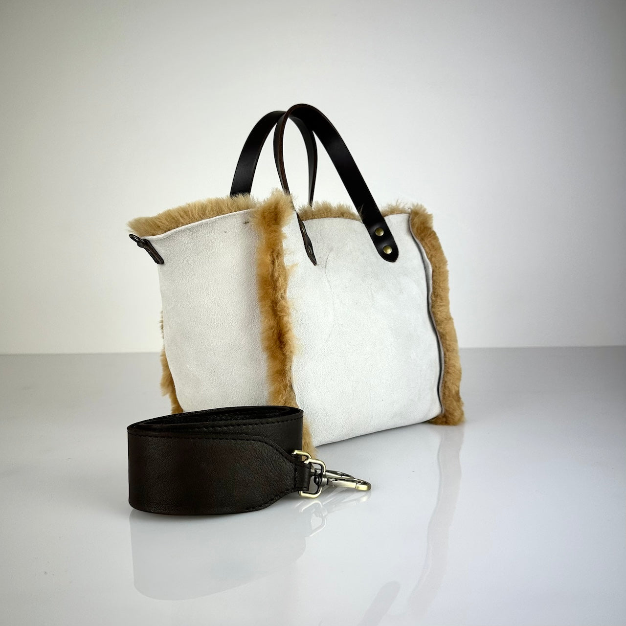 Diese HANDBAG SHEARLING REVERSIBLE, MEDIUM von LABEL17 wird aus luxuriösem Merino-Lammfell gefertigt, das der Tasche einen einzigartigen und stilvollen Look verleiht. Mit dunkelbraunen Griffen aus Sattlerleder und einem abnehmbaren Schulterriemen bietet sie vielseitige Tragemöglichkeiten, egal ob in der Hand oder als Crossbody.
Diese reversible Tasche ist ein Meisterwerk der Schweizer Handwerkskunst und vereint schlichtes Design mit hochwertiger Sattlerarbeit. Jede Tasche ist ein Unikat.