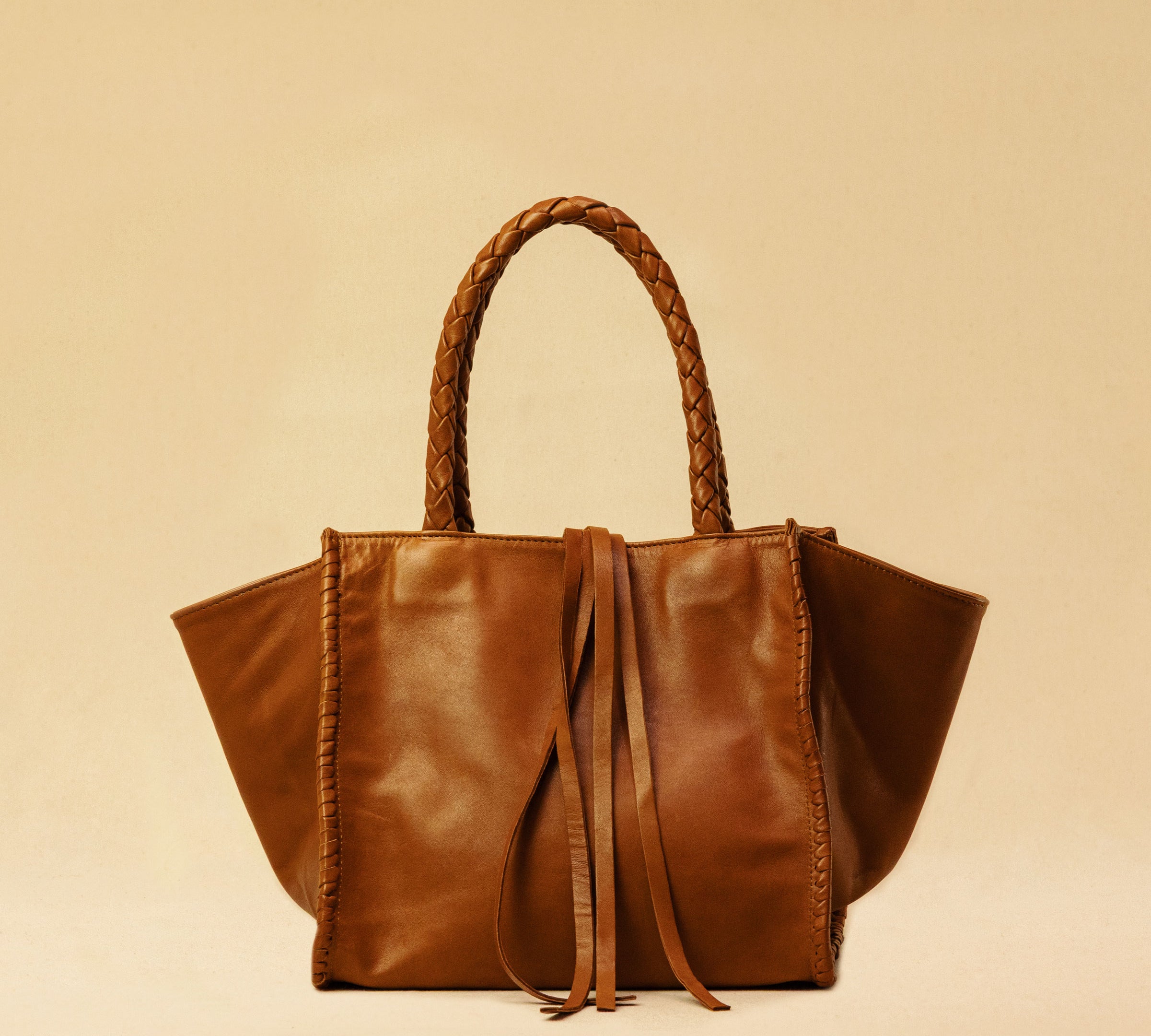 The Shoulder Bag IVY, crafted from supple, vegetable-tanned nappa leather, stands out for its artisanal detailing, distinctive side seams, and long braided handles. The interior lining and zippered side pocket are also made of fine nappa leather.