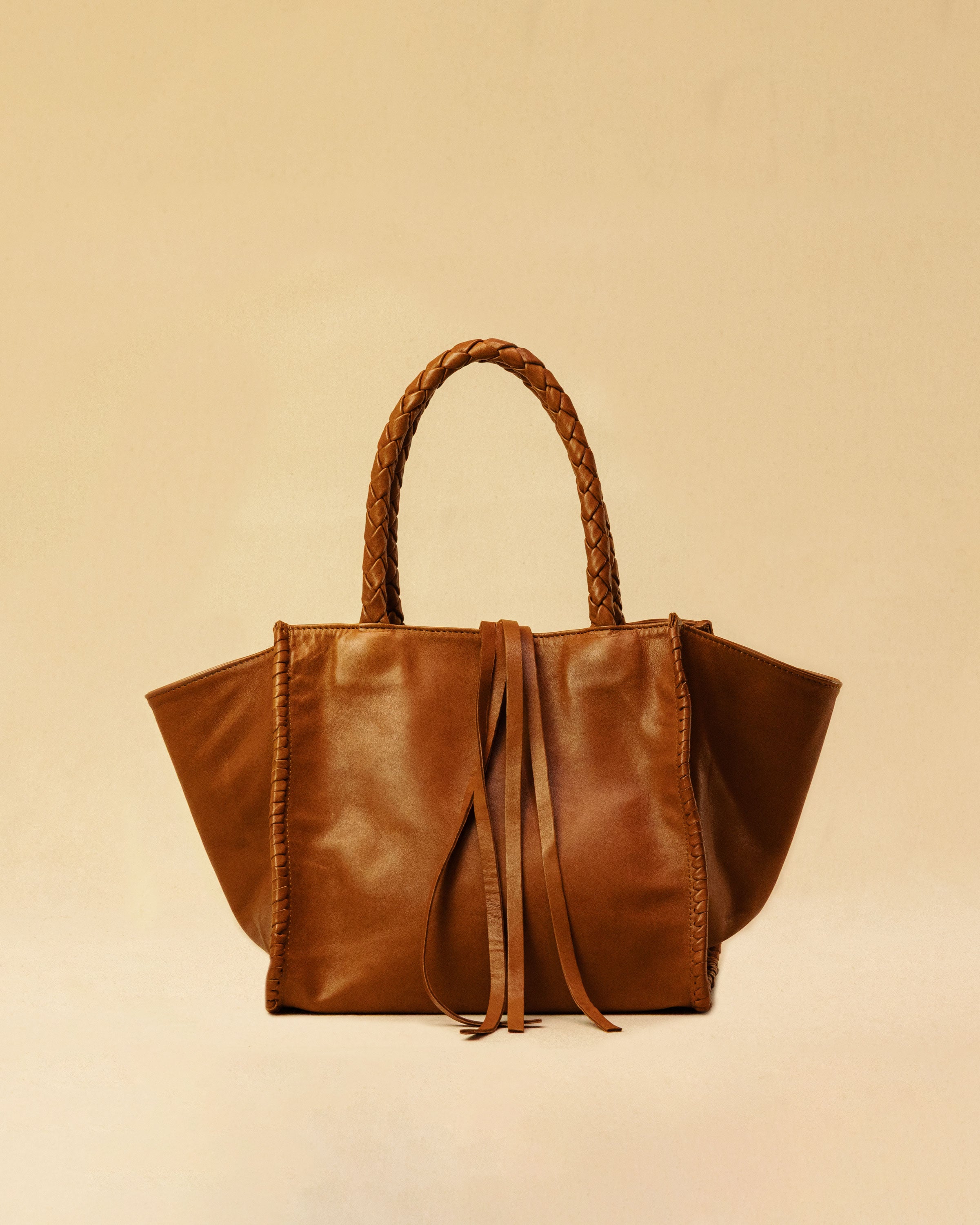 The Shoulder Bag IVY, crafted from supple, vegetable-tanned nappa leather, stands out for its artisanal detailing, distinctive side seams, and long braided handles. The interior lining and zippered side pocket are also made of fine nappa leather.