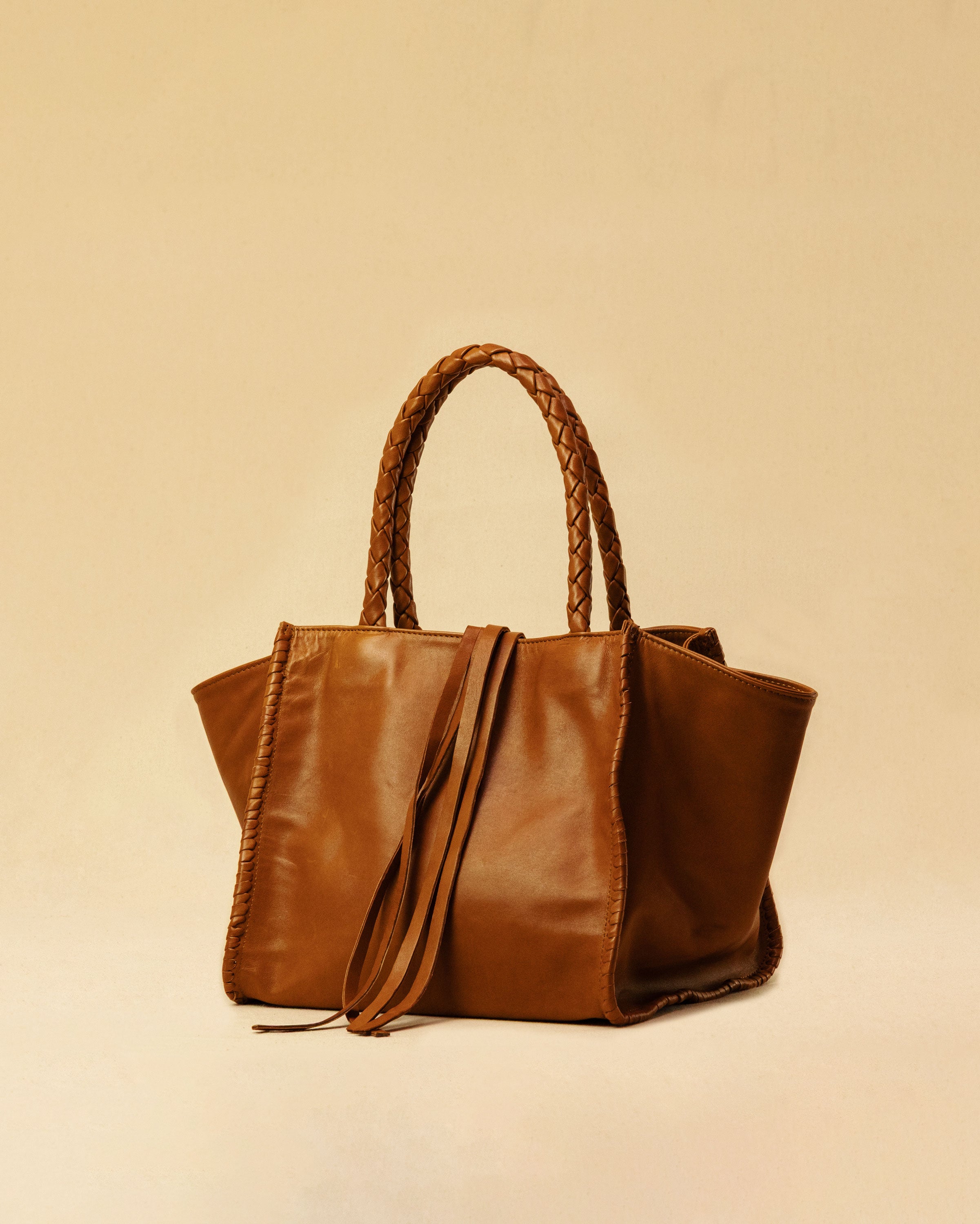 The Shoulder Bag IVY, crafted from supple, vegetable-tanned nappa leather, stands out for its artisanal detailing, distinctive side seams, and long braided handles. The interior lining and zippered side pocket are also made of fine nappa leather.