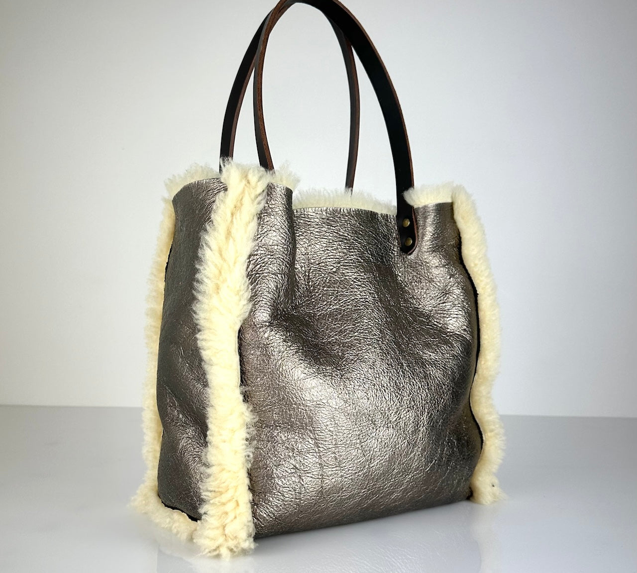 Die Shoulder Bag Reversible Snow von LABEL17 wird aus luxuriösem Merino-Lammfell gefertigt. Mit langen dunkelbraunen Schulterriemen aus Sattlerleder kann die Tasche über die Schulter getragen werden.
Diese reversible Tasche ist ein Meisterwerk der Schweizer Handwerkskunst und vereint schlichtes Design mit hochwertiger Sattlerarbeit. Jede Tasche ist ein Unikat.