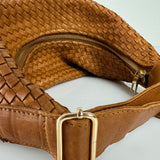 The LABEL17 Shoulder Bag Saddle Tresse is braided by hand and crafted from the most supple Nappa leather exemplifying luxury and durability. Designed with a unique saddle shape, it conforms seamlessly to your body. The bag is lined with leather and has practical compartments, including a zippered compartment for safe storage. Featuring a zipper and an adjustable shoulder strap, this versatile accessory offers the freedom to be worn over the shoulder or across the body.