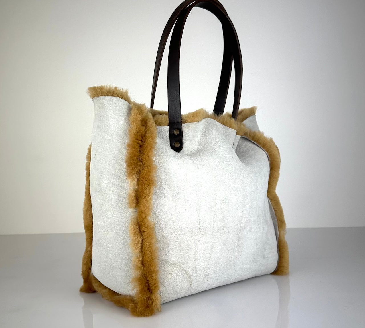 Die Shoulder Bag Reversible Snow von LABEL17 wird aus luxuriösem Merino-Lammfell gefertigt. Mit langen dunkelbraunen Schulterriemen aus Sattlerleder kann die Tasche über die Schulter getragen werden.
Diese reversible Tasche ist ein Meisterwerk der Schweizer Handwerkskunst und vereint schlichtes Design mit hochwertiger Sattlerarbeit. Jede Tasche ist ein Unikat.