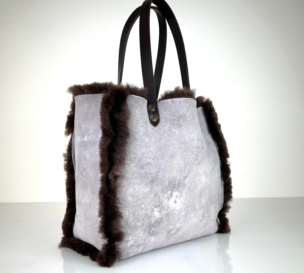 Die Shoulder Bag Reversible Snow von LABEL17 wird aus luxuriösem Merino-Lammfell gefertigt. Mit langen dunkelbraunen Schulterriemen aus Sattlerleder kann die Tasche über die Schulter getragen werden.
Diese reversible Tasche ist ein Meisterwerk der Schweizer Handwerkskunst und vereint schlichtes Design mit hochwertiger Sattlerarbeit. Jede Tasche ist ein Unikat.