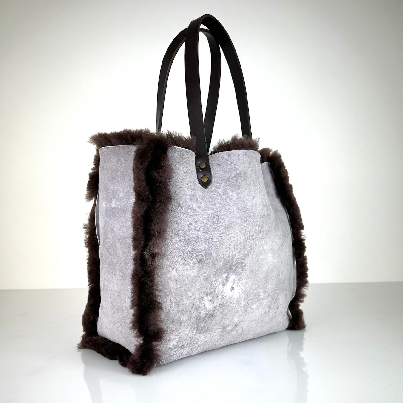 Die Shoulder Bag Reversible Snow von LABEL17 wird aus luxuriösem Merino-Lammfell gefertigt. Mit langen dunkelbraunen Schulterriemen aus Sattlerleder kann die Tasche über die Schulter getragen werden.
Diese reversible Tasche ist ein Meisterwerk der Schweizer Handwerkskunst und vereint schlichtes Design mit hochwertiger Sattlerarbeit. Jede Tasche ist ein Unikat.