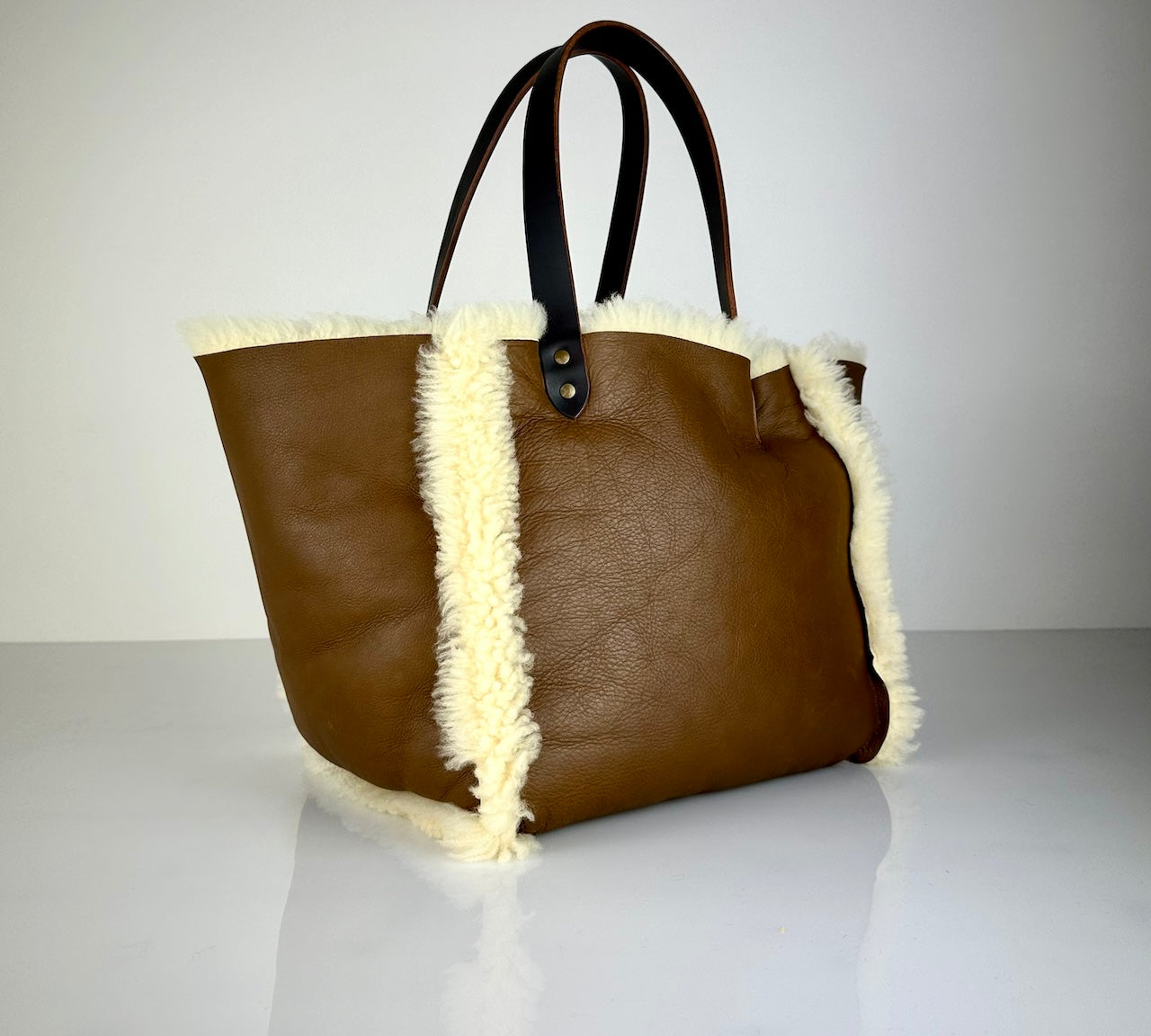 Die SHOULDER BAG SHEARLING REVERSIBLE von LABEL17 wird aus luxuriösem Merino-Lammfell gefertigt, das der Tasche einen einzigartigen und stilvollen Look verleiht. Mit langen dunkelbraunen Schulterriemen aus Sattlerleder kann die Tasche bequem über die Schulter getragen werden.
Diese reversible Tasche ist ein Meisterwerk der Schweizer Handwerkskunst und vereint schlichtes Design mit hochwertiger Sattlerarbeit. Jede Tasche ist ein Unikat.