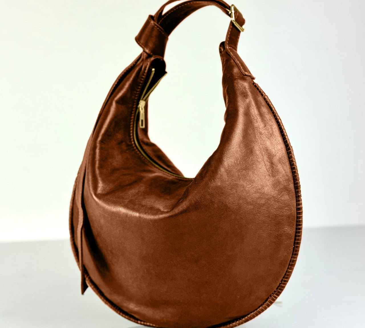 Shoulder Bag Saddle IVY in Caramel Brown: leichte und elegante Schulter- und Umhängetasche von LABEL17. Handgefertigt aus geschmeidigem, pflanzlich gegerbtem Lamm-Nappaleder mit Innenfutter aus Leder und inwendigen Innentaschen und Reissverschluss, tragbar als Handtasche, Schultertasche oder Crossbody.